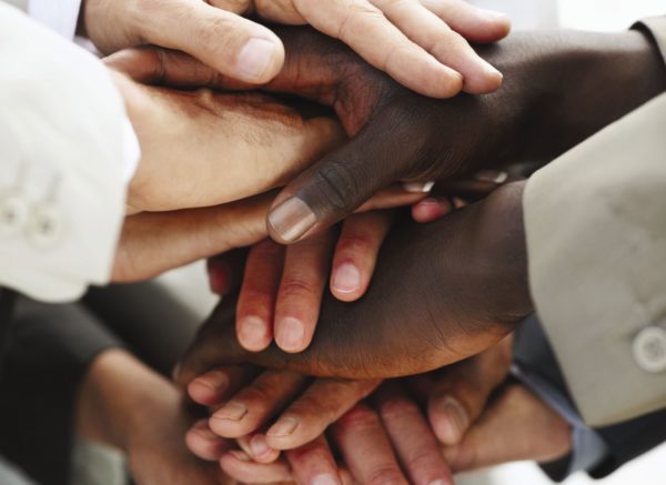 Closeup image of hands of businesspeople on top of each other as symbol of their partnership